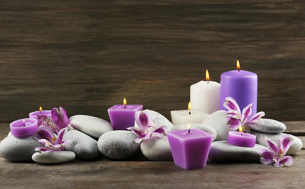 Spa ancora in vita con fiori viola ciottoli e lume di candela su sfondo di legno