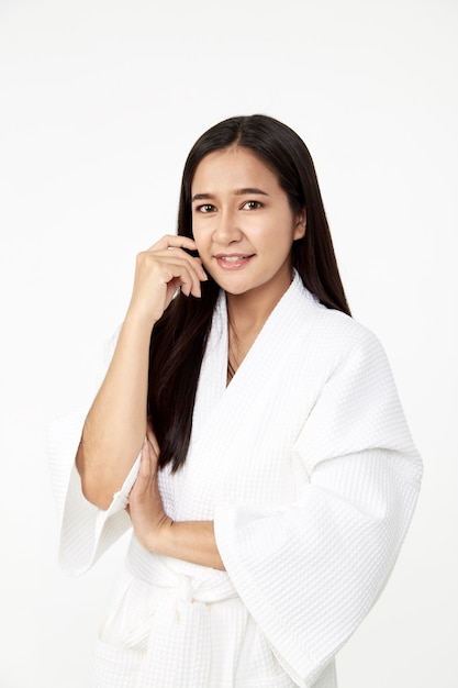 Spa skincare beauty donna asiatica che indossa un accappatoio con un sorriso che tocca la pelle morbida isolata su sfondo bianco