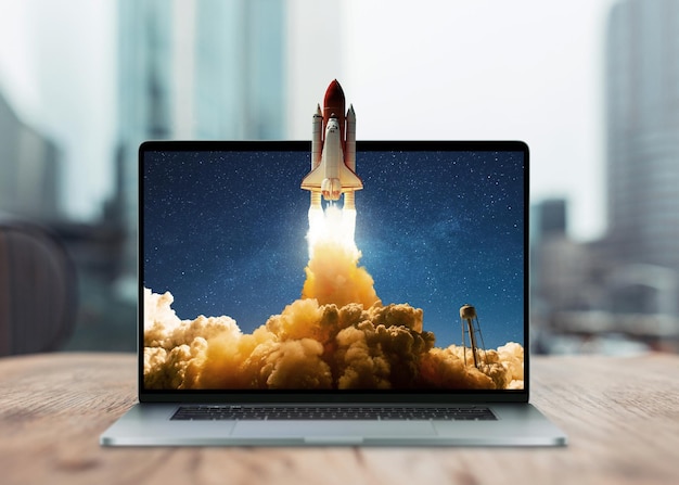 space rocket shuttle with a cloud of smoke and blast takes off from a laptop on a working office desk creative idea and startup successful business project go outside the frame