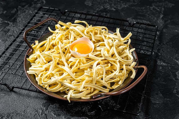 Spaetzle secco noodle all'uovo in un vassoio di acciaio Sfondo nero Vista dall'alto