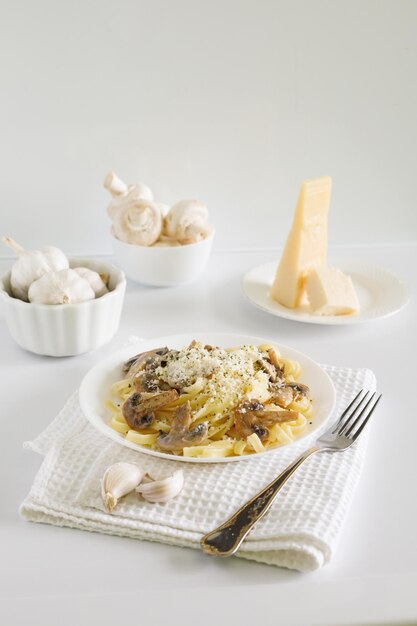 spaghetti ai funghi e parmigiano in salsa cremosa su un tavolo bianco