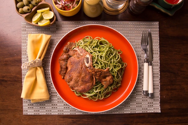 Spaghetti al pesto di salsa verde con braciola di maiale Cucina tradizionale peruviana del comfort food fatta in casa