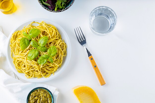 Spaghetti al pesto e basilico su fondo bianco