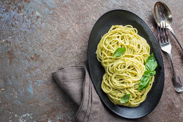 Spaghetti al pesto fatto in casa in un piatto nero, vista dall'alto