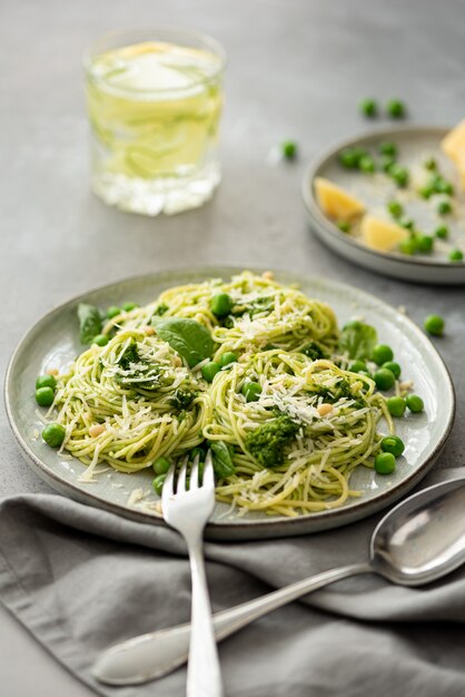 Spaghetti al pesto, parmigiano e piselli in un piatto grigio