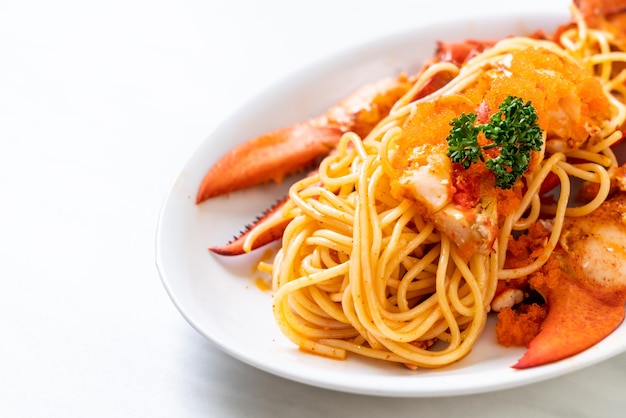 spaghetti all'aragosta con uovo di gamberi su piatto bianco