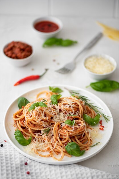 Spaghetti alla bolognese con basilico e parmigiano su un piatto bianco