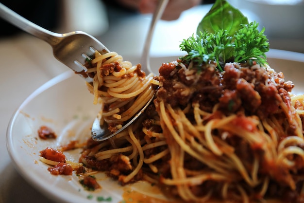 Spaghetti alla bolognese con carne macinata e salsa di pomodoro guarniti con parmigiano e basilico, cibo italiano
