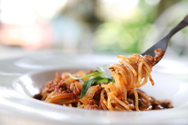 Spaghetti alla bolognese con carne macinata e salsa di pomodoro guarniti con parmigiano e basilico, cibo italiano