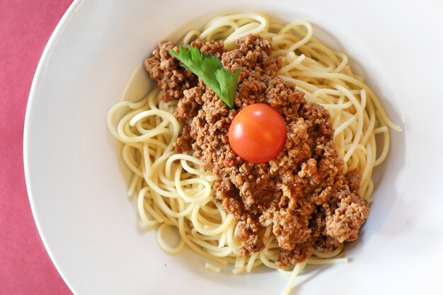 Spaghetti alla bolognese con parmigiano e basilico in un piatto