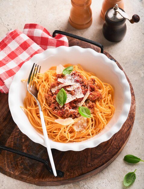 Spaghetti alla bolognese Gustosi spaghetti italiani appetitosi con salsa alla bolognese salsa di pomodoro formaggio parmigiano e basilico su piatto bianco su pietra grigia o cemento sullo sfondo del tavolo Vista dall'alto