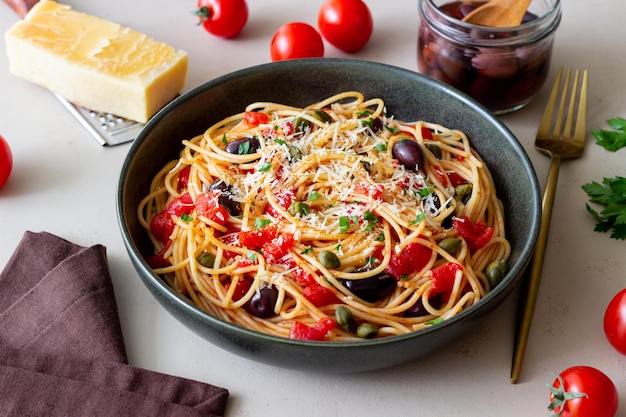 Spaghetti alla puttanesca con capperi olive Kalamata formaggio pomodori e acciughe Cibo italiano