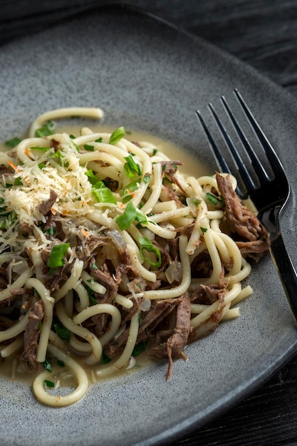 Spaghetti appetitosi con carne ed erbe aromatiche su un piatto su un tavolo in un ristorante Primo piano verticale