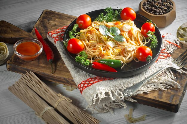 Spaghetti bolliti con condimenti e verdure su uno sfondo vecchio