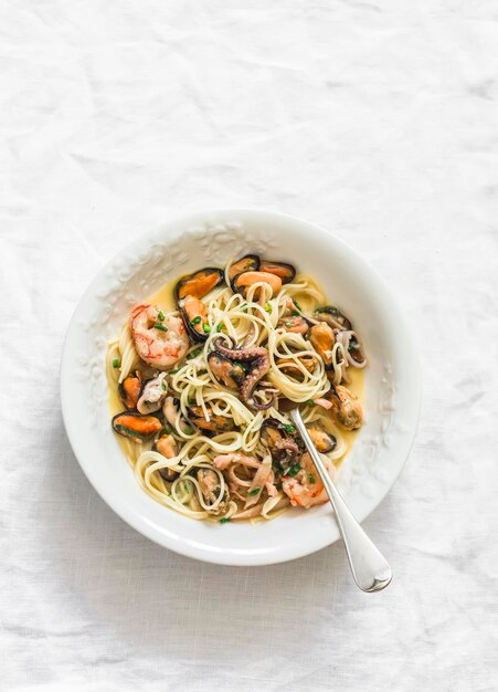 Spaghetti con frutti di mare in salsa di vino su uno sfondo chiaro vista dall'alto