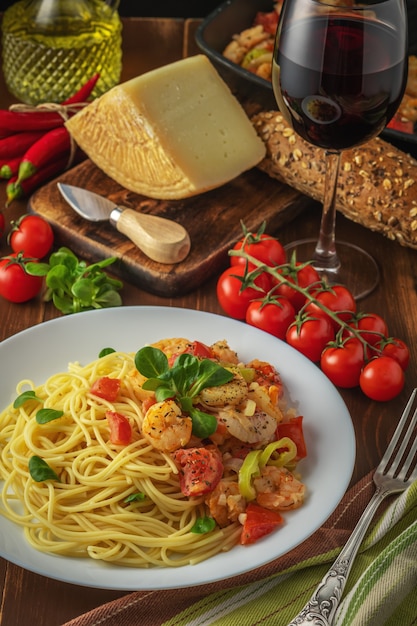 Spaghetti con gamberetti pomodorini e spezie sulla scena in legno