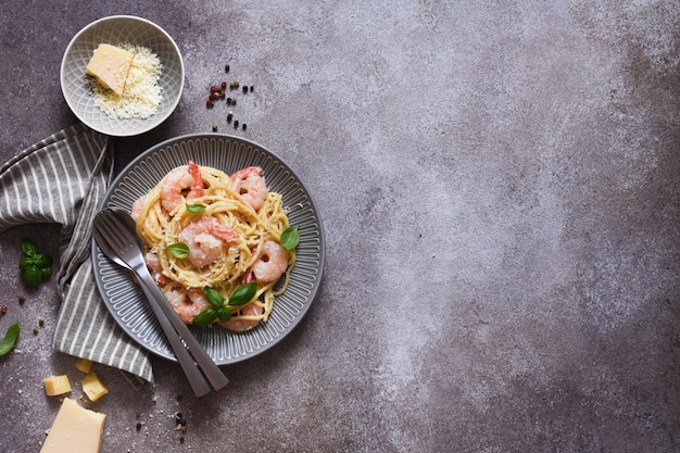 Spaghetti con gamberi, con salsa e parmigiano su un fondo di cemento. Vista dall'alto. Menù. Pasta ai gamberetti.