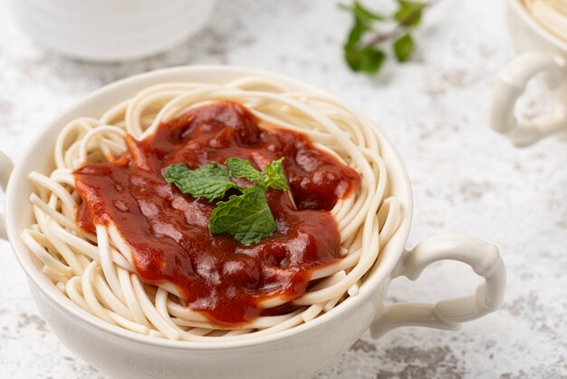 spaghetti con la salsa di pomodori su superficie bianca