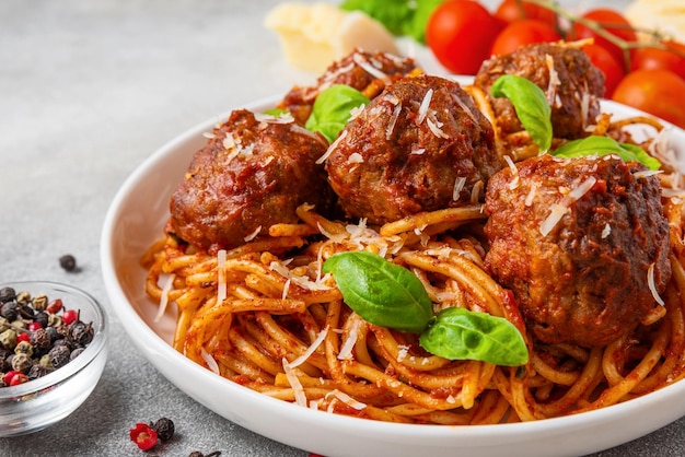 Spaghetti con polpette in salsa di pomodoro coperte di formaggio parmigiano e foglie di basilico fresco in un