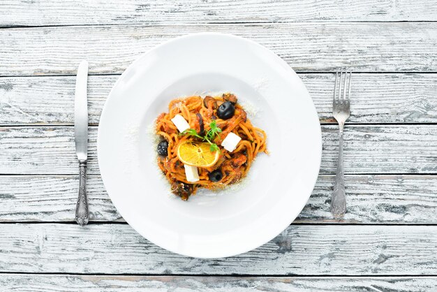 Spaghetti con pomodori, olive e feta in un piatto Vista dall'alto Spazio libero per il testo