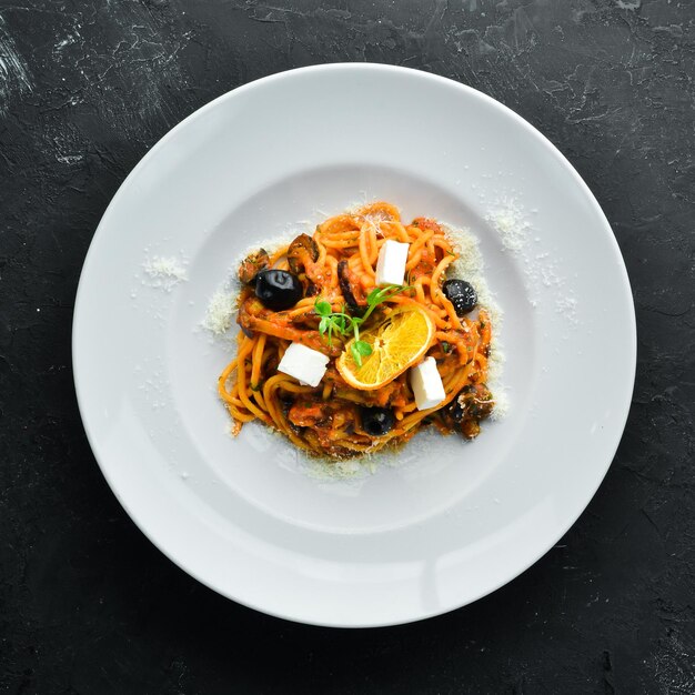 Spaghetti con pomodori, olive e feta in un piatto. Vista dall'alto. Spazio libero per il tuo testo.