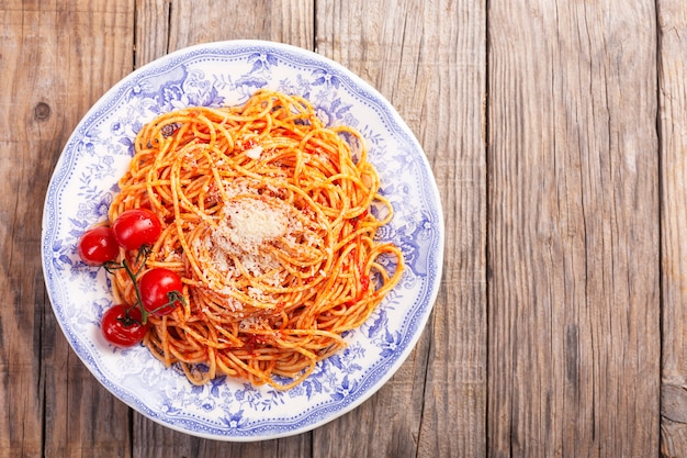 Spaghetti con salsa al pomodoro e pomodori ciliegia su una tavola rustica di legno