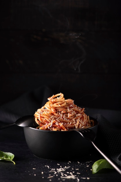 Spaghetti con salsa di pomodoro e parmigiano in ciotola nera