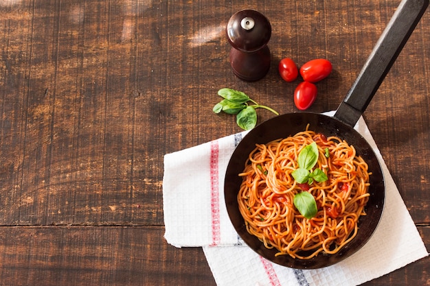 Spaghetti cotti con basilico e pomodori sul tavolo di legno