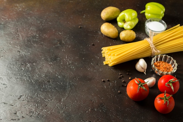 Spaghetti crudi con ingredienti sullo sfondo marrone