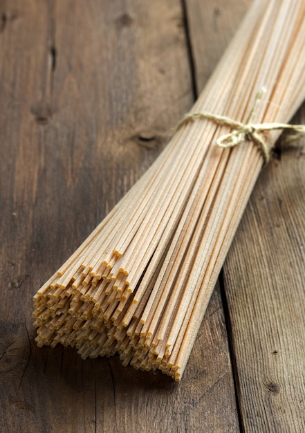 Spaghetti crudi del grano intero su una fine di legno marrone della tavola su