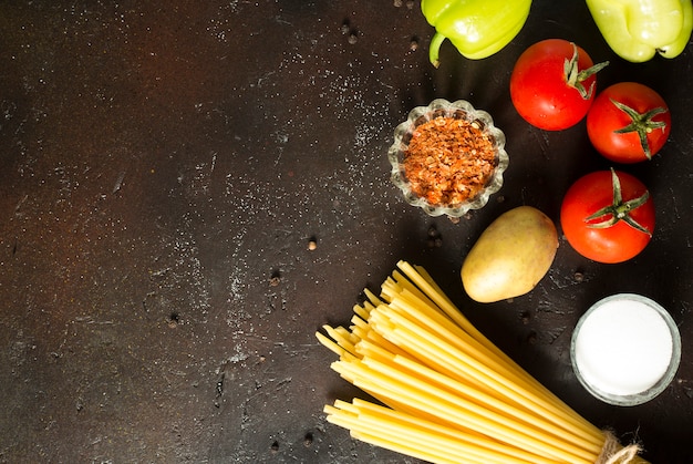 Spaghetti crudi dell'alimento italiano variopinto fresco saporito sul fondo nero del tavolo da cucina kitchen