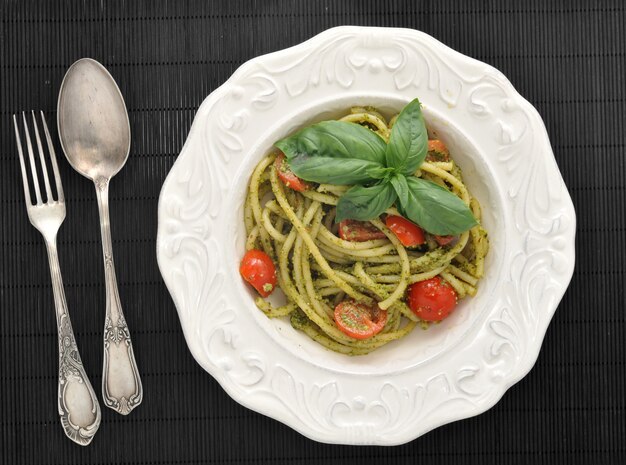 Spaghetti della pasta con i pomodori ciliegia e il basilikum in un piatto