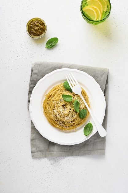 Spaghetti di pasta al pesto e foglie di basilico fresco in una ciotola bianca