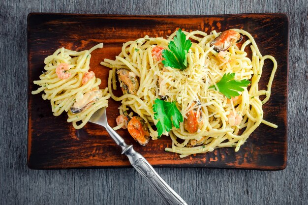 Spaghetti di pasta con frutti di mare in salsa cremosa su un tavolo di legno in stile rustico.