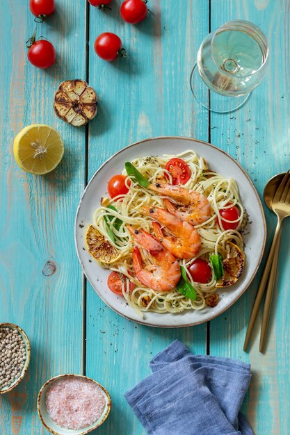 Spaghetti di pasta con gamberi, pomodori, aglio, spinaci e limone. Cucina italiana. Frutti di mare. Dieta.