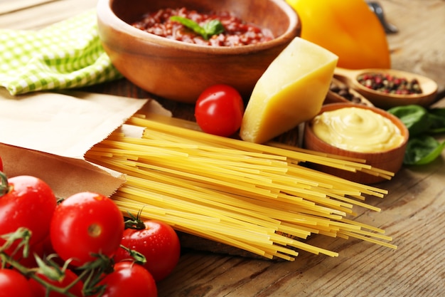 Spaghetti di pasta con pomodoro, salsa bolognese, formaggio e basilico su fondo di legno rustico