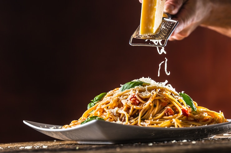 Foto spaghetti di pasta italiana con salsa di pomodoro basilico e parmigiano in piatto bianco.