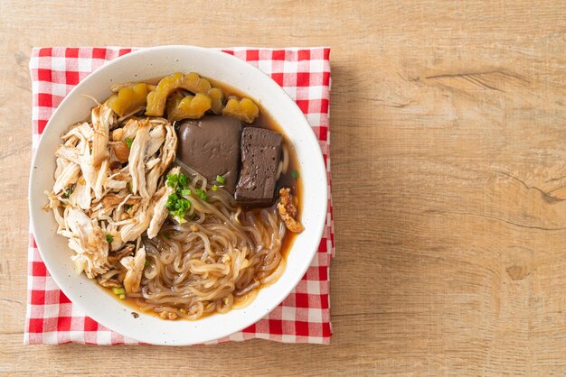 Spaghetti di pollo stufati in una ciotola di zuppa marrone - stile asiatico dell'alimento