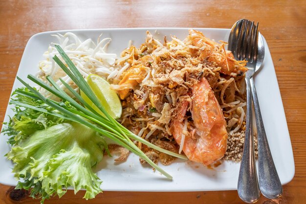 Spaghetti di riso saltati in padella Pad Thai con gamberi d'acqua dolce serviti con germogli di verdure e limone