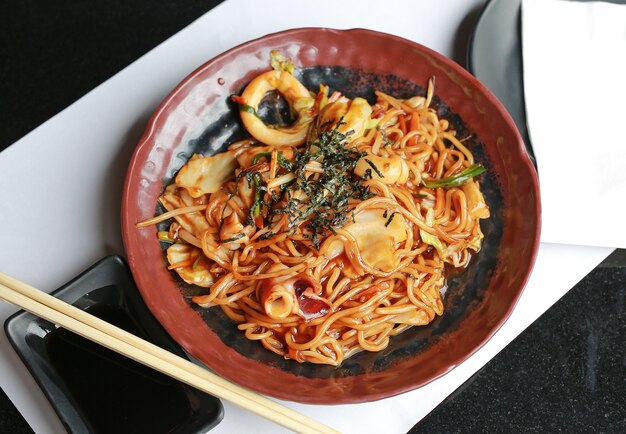 Spaghetti giapponesi yakisoba in piatto di ceramica marrone