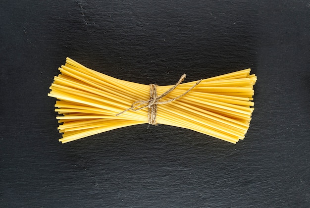Spaghetti grezzi legati con una corda su una priorità bassa nera