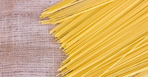 Spaghetti grezzi su una vecchia tela di sacco marrone