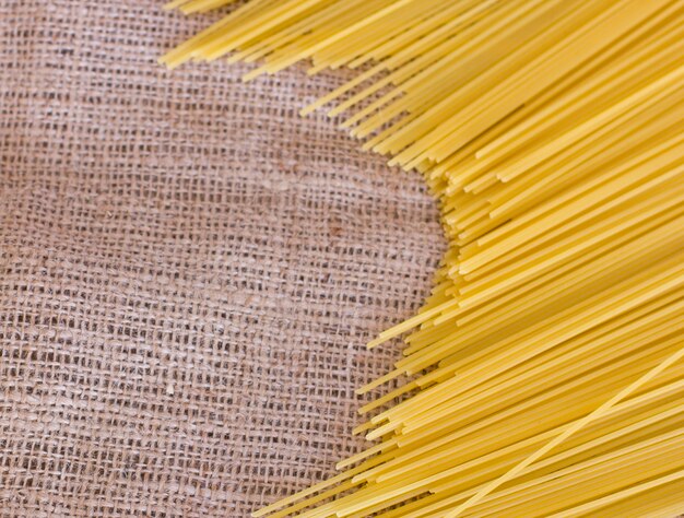 Spaghetti grezzi su una vecchia tela di sacco marrone