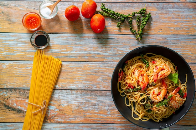 Spaghetti integrali con gamberetti in padella su pietra ardesia blu o fondo in cemento