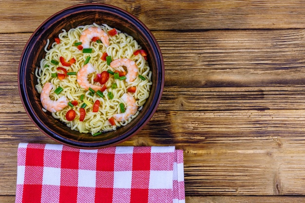 Spaghetti istantanei con gamberetti peperone rosso e cipolla verde in una ciotola di ceramica Cibo giapponese Vista dall'alto