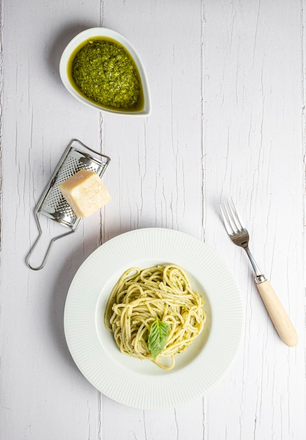 Spaghetti italiani con pesto fresco fatto in casa Mangiati su una tavola di legno bianca