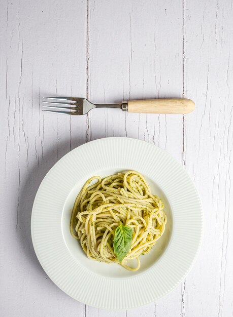 Spaghetti italiani con pesto fresco fatto in casa Mangiati su una tavola di legno bianca