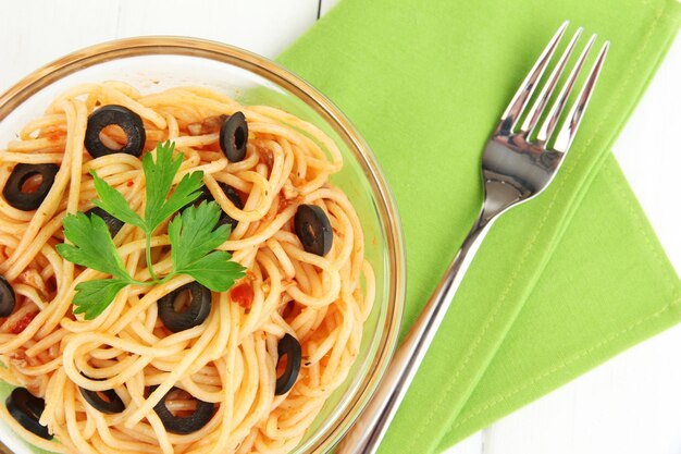 Spaghetti italiani in ciotola di vetro sul primo piano di legno della tavola