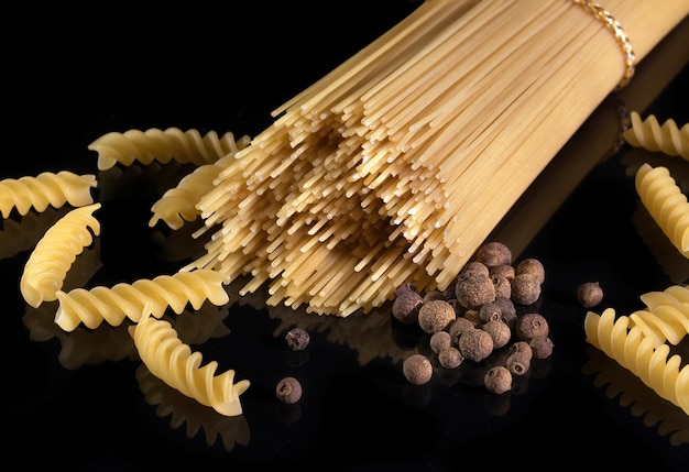 Spaghetti italiani isolati su sfondo nero Pasta italiana gialla pepe nero