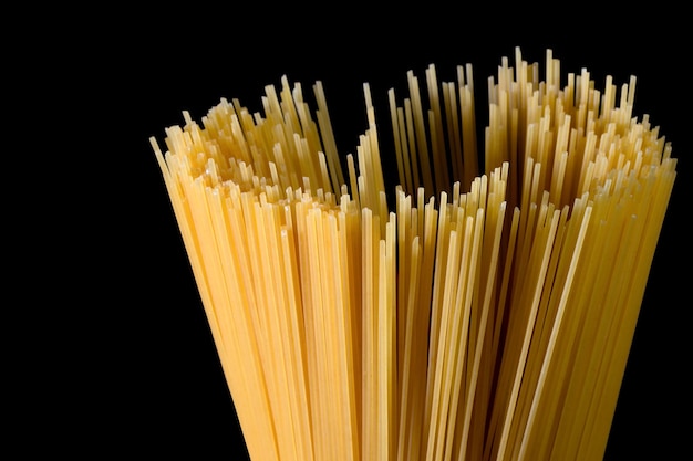 Spaghetti lunghi gialli su sfondo nero Pasta sottile disposta in file. Pasta italiana gialla